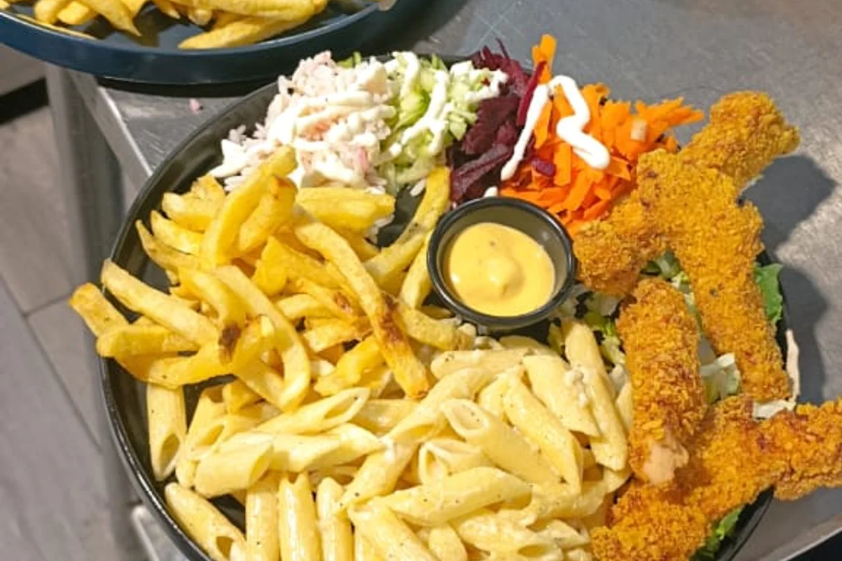Assiette de poulet croustillant avec pâtes, frites et salade